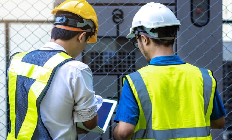 Dos trabajadores de campo inspeccionan la red eléctrica