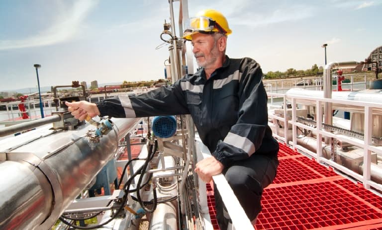 Trabajador de campo junto a grandes tuberías