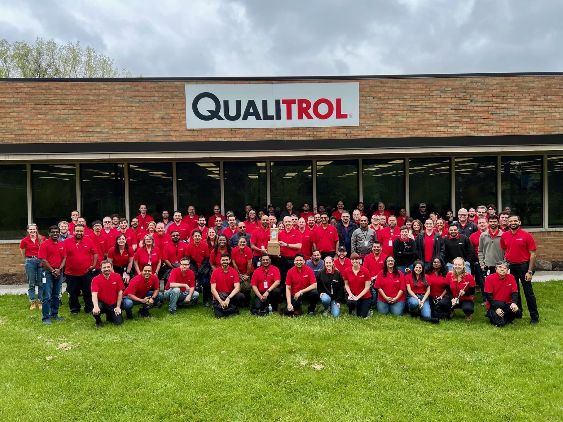Foto del equipo de Qualitrol con empleados usando camisas rojas de la empresa en las instalaciones de Fairport